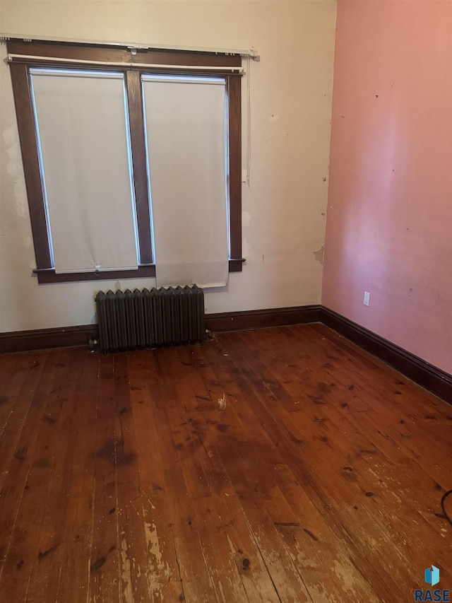 empty room featuring radiator heating unit and hardwood / wood-style flooring