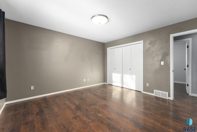 unfurnished bedroom with dark wood-type flooring and a closet