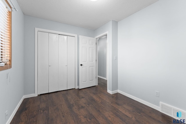 unfurnished bedroom featuring dark hardwood / wood-style flooring, a closet, and a textured ceiling