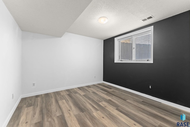 empty room featuring wood-type flooring and a textured ceiling