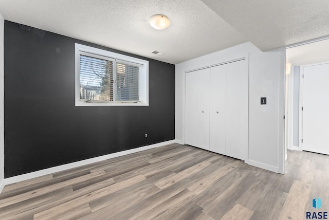 unfurnished bedroom with a closet, a textured ceiling, and hardwood / wood-style flooring