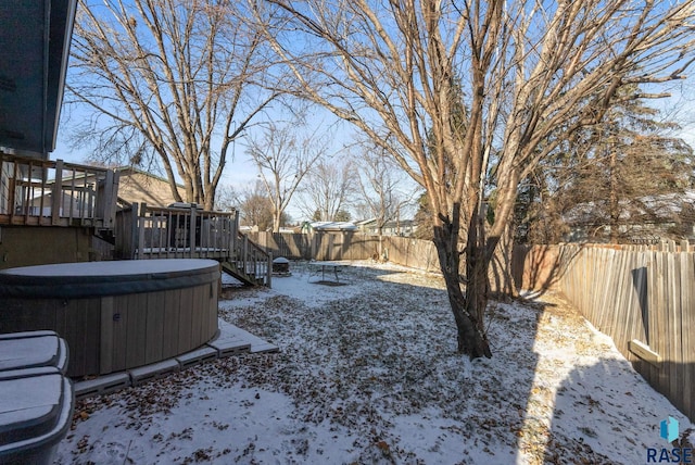 yard covered in snow featuring a wooden deck and a hot tub