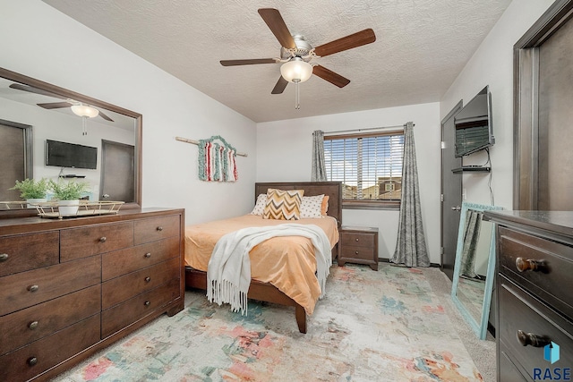 carpeted bedroom with ceiling fan and a textured ceiling