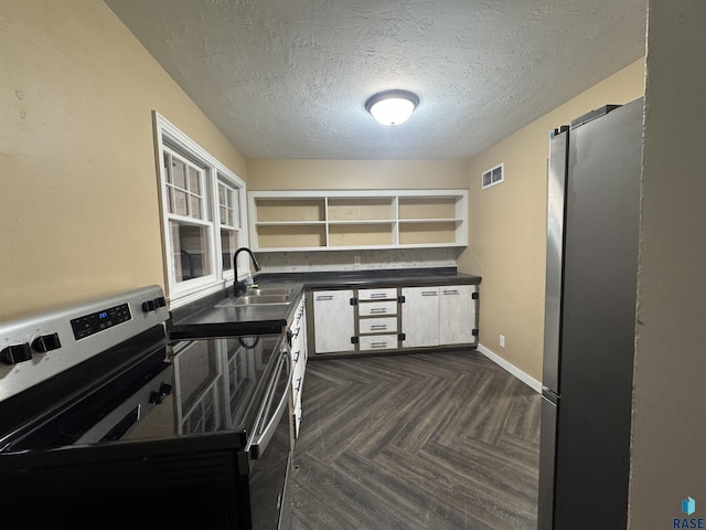 kitchen with appliances with stainless steel finishes, dark parquet flooring, a textured ceiling, sink, and white cabinetry