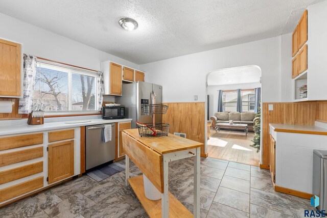 kitchen featuring a textured ceiling, plenty of natural light, light hardwood / wood-style floors, and stainless steel appliances