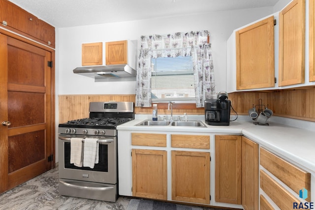 kitchen with a textured ceiling, gas stove, extractor fan, sink, and wood walls