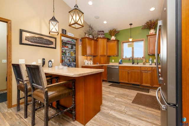 kitchen with kitchen peninsula, pendant lighting, stainless steel appliances, and a breakfast bar area