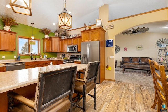 kitchen featuring hanging light fixtures, stainless steel appliances, lofted ceiling, and light wood-type flooring