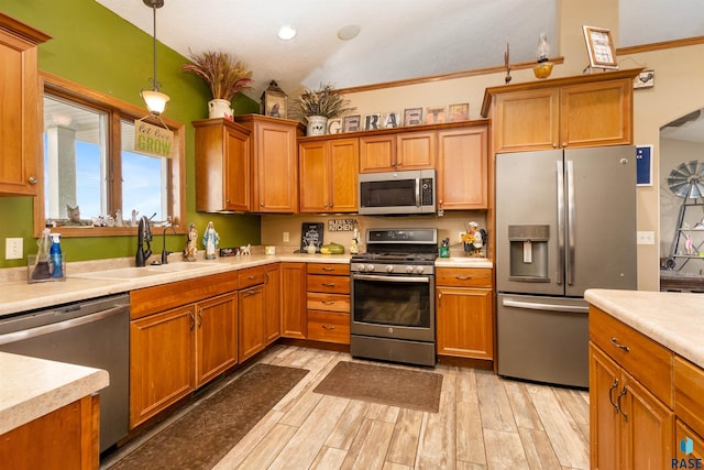 kitchen featuring decorative light fixtures, light wood-type flooring, ornamental molding, and appliances with stainless steel finishes