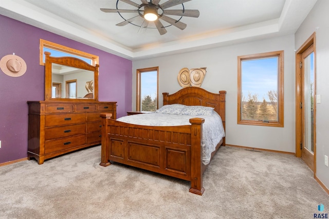 carpeted bedroom with a tray ceiling and ceiling fan