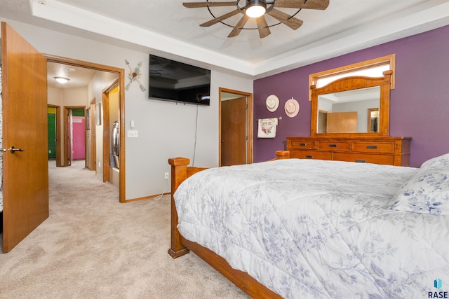 bedroom with a tray ceiling, ceiling fan, and light colored carpet