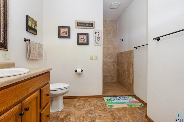 bathroom with vanity, toilet, and tiled shower