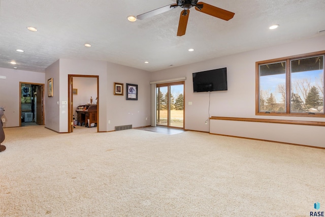 unfurnished living room featuring ceiling fan, light colored carpet, and a textured ceiling