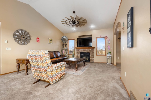 living room featuring carpet flooring, ceiling fan, a stone fireplace, and vaulted ceiling