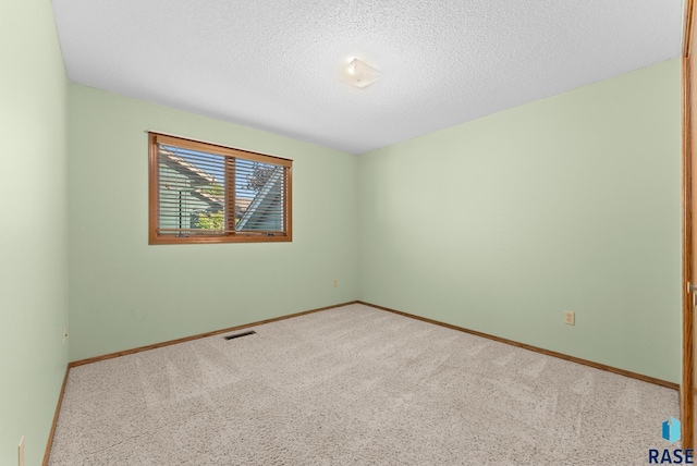 unfurnished room with light colored carpet and a textured ceiling