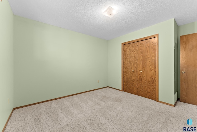 unfurnished bedroom featuring light carpet, a closet, and a textured ceiling