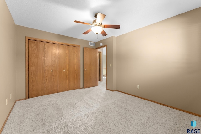 unfurnished bedroom featuring a closet, ceiling fan, and light colored carpet