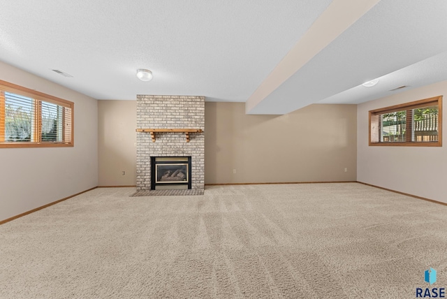 unfurnished living room featuring a fireplace, light carpet, plenty of natural light, and a textured ceiling