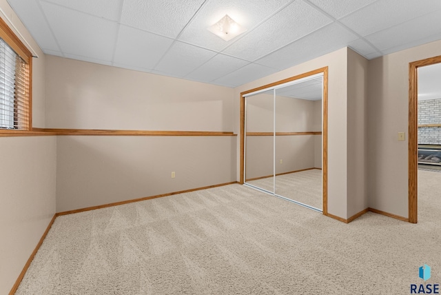 unfurnished bedroom with light carpet, a closet, and a drop ceiling