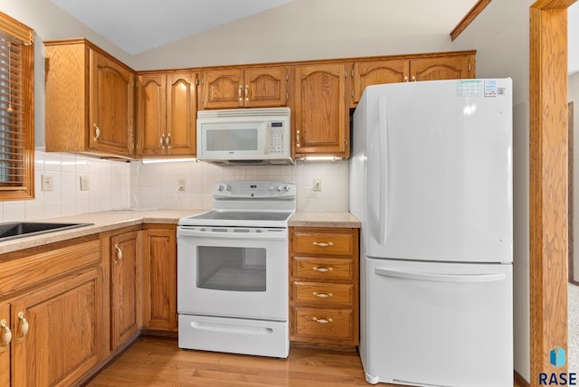 kitchen with white appliances, backsplash, sink, light hardwood / wood-style flooring, and vaulted ceiling