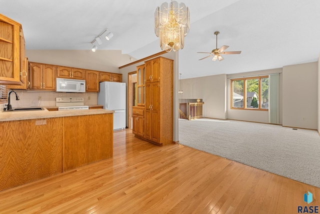 kitchen featuring kitchen peninsula, white appliances, sink, light hardwood / wood-style flooring, and lofted ceiling