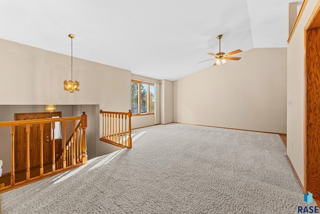 carpeted empty room with ceiling fan with notable chandelier and vaulted ceiling