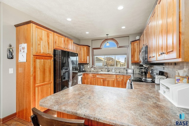 kitchen featuring a kitchen breakfast bar, sink, hanging light fixtures, kitchen peninsula, and stainless steel appliances