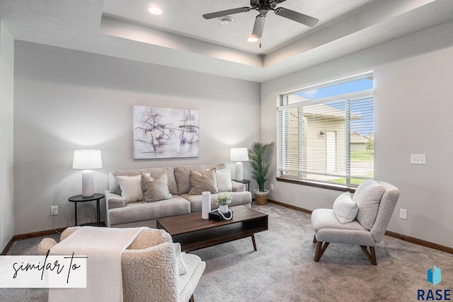 carpeted living room with a raised ceiling and ceiling fan