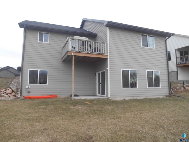 rear view of house featuring a yard and a balcony