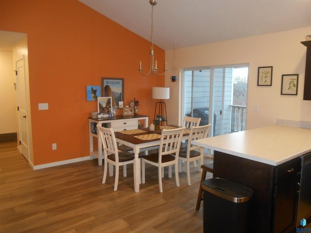 dining area featuring light wood-type flooring, an inviting chandelier, and vaulted ceiling