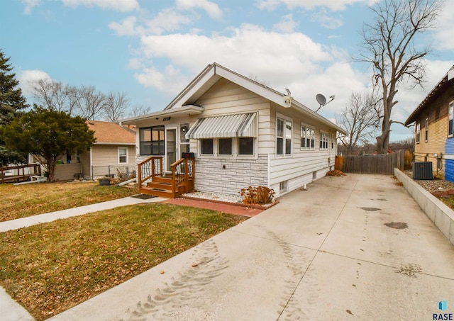 bungalow-style house featuring cooling unit and a front lawn