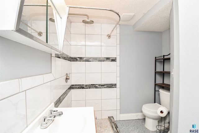 bathroom with a textured ceiling, sink, toilet, and tiled shower