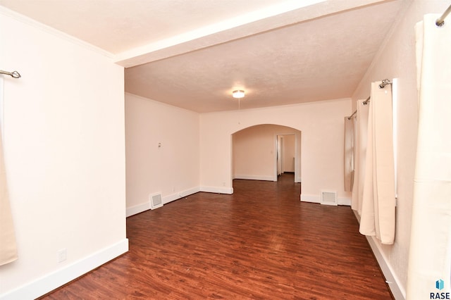 spare room featuring a textured ceiling, ornamental molding, and dark wood-type flooring