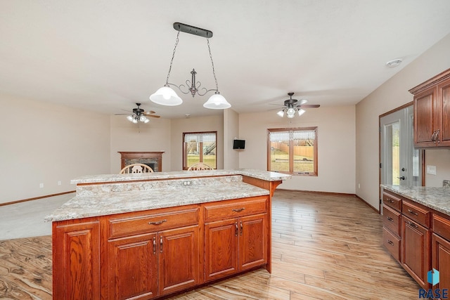 kitchen featuring ceiling fan with notable chandelier, decorative light fixtures, a kitchen island, and light hardwood / wood-style flooring