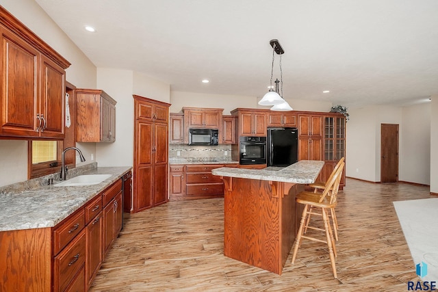 kitchen with black appliances, sink, light hardwood / wood-style flooring, decorative backsplash, and a kitchen island