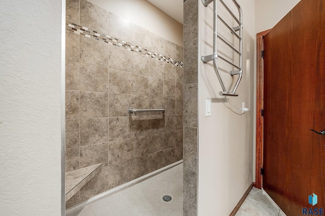 bathroom with a tile shower and tile patterned flooring