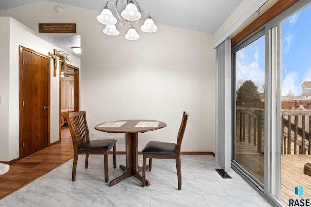 dining room with light hardwood / wood-style floors, vaulted ceiling, and an inviting chandelier