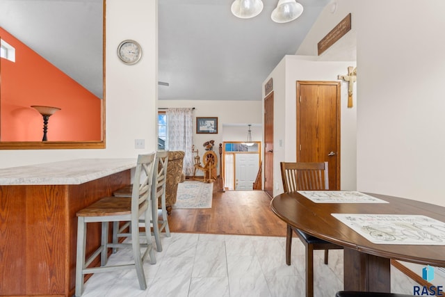 dining space featuring vaulted ceiling and light wood-type flooring