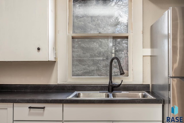 kitchen featuring white cabinetry, stainless steel fridge, and sink