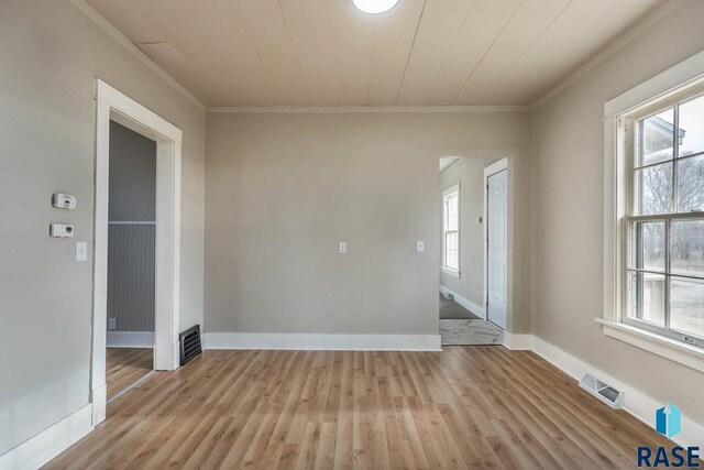 spare room featuring crown molding, a healthy amount of sunlight, and light hardwood / wood-style floors