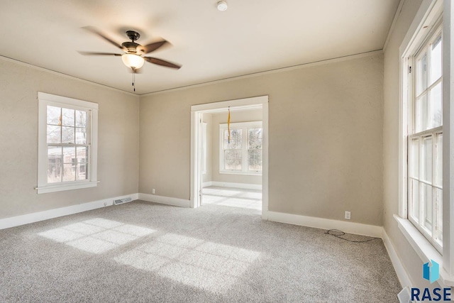 unfurnished room featuring ceiling fan, plenty of natural light, and light colored carpet