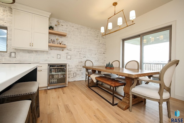 kitchen featuring white cabinetry, light hardwood / wood-style flooring, beverage cooler, and decorative light fixtures