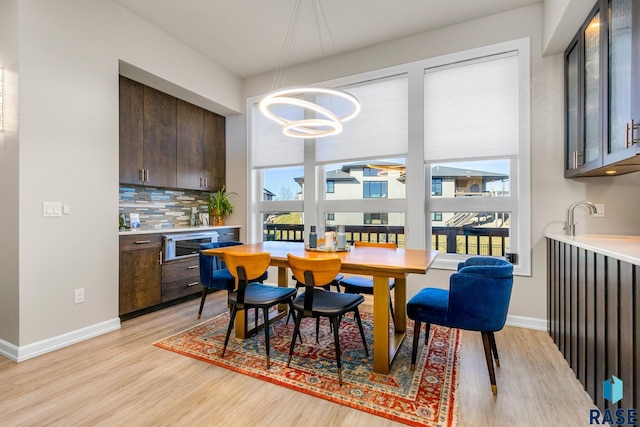 dining area with light hardwood / wood-style floors, sink, and a chandelier