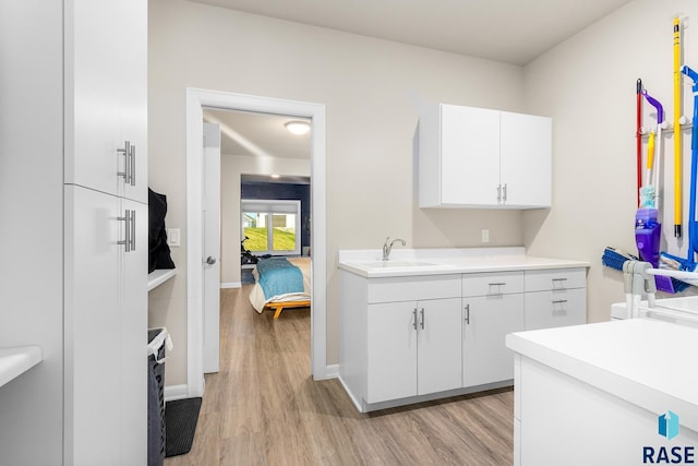 kitchen with white cabinetry, sink, and light hardwood / wood-style floors