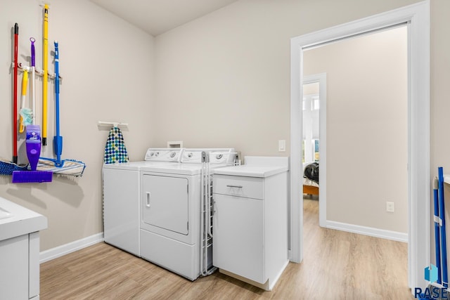 laundry room featuring cabinets, light wood-type flooring, and washing machine and dryer