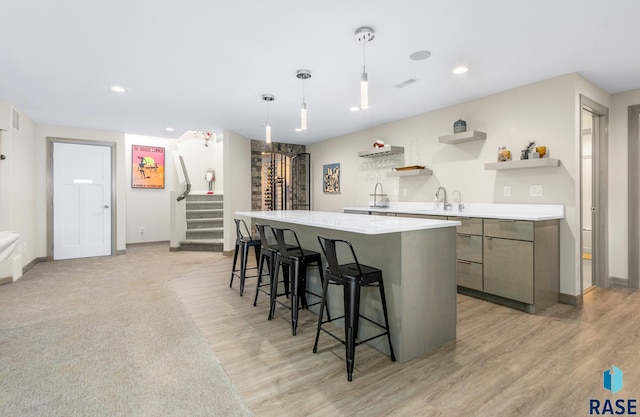 kitchen featuring decorative light fixtures, a center island, light wood-type flooring, and sink