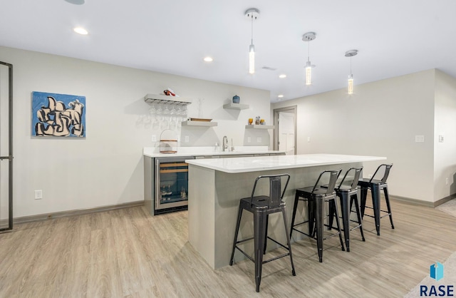 kitchen featuring pendant lighting, a kitchen breakfast bar, wine cooler, light hardwood / wood-style floors, and a kitchen island