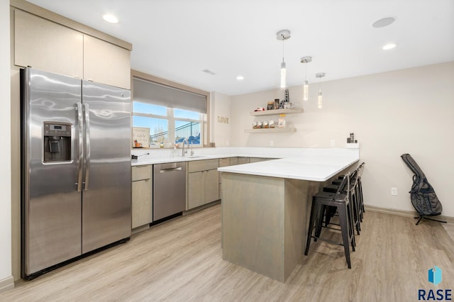 kitchen featuring kitchen peninsula, light hardwood / wood-style flooring, hanging light fixtures, and appliances with stainless steel finishes