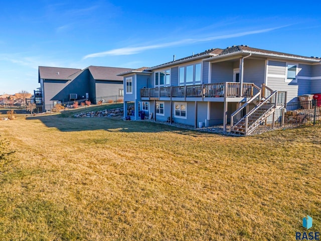 rear view of house featuring a wooden deck and a lawn