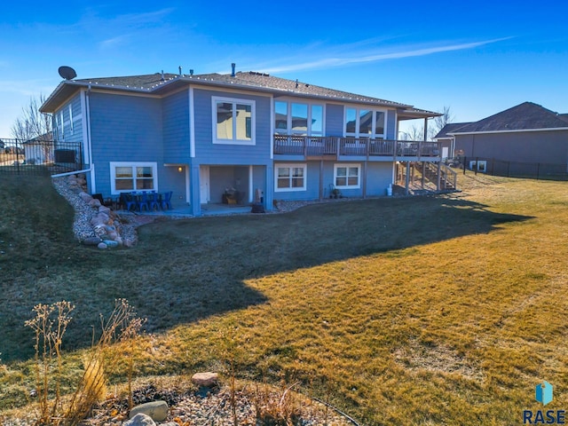 back of house featuring a patio, a wooden deck, and a lawn